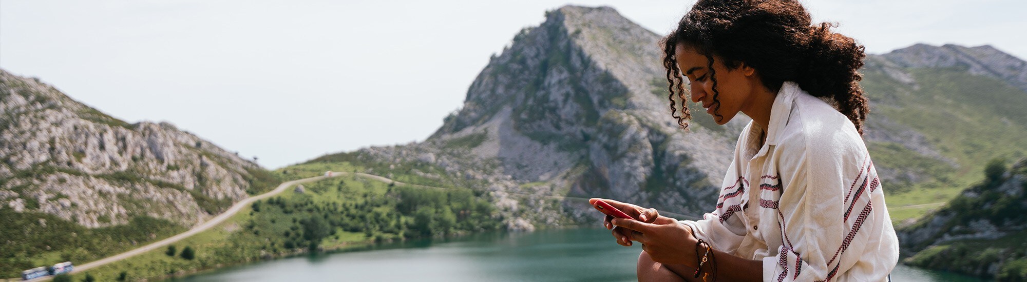 A woman looking at her phone with a mountain in the background.